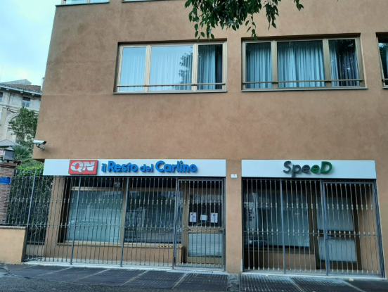 foto dellafacciata di un palazzo con a piano terra le vetrine di due attività, a destra speed e a sinistra resto del carlino