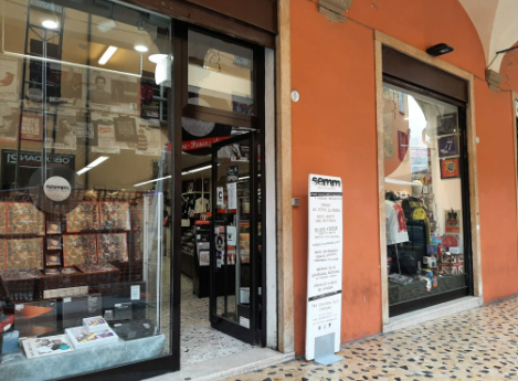 foto dell'entrata delnegozio di musica semm di bologna sotto i portici, con in primo piano il muro arancione, la vetrina piena di dischi