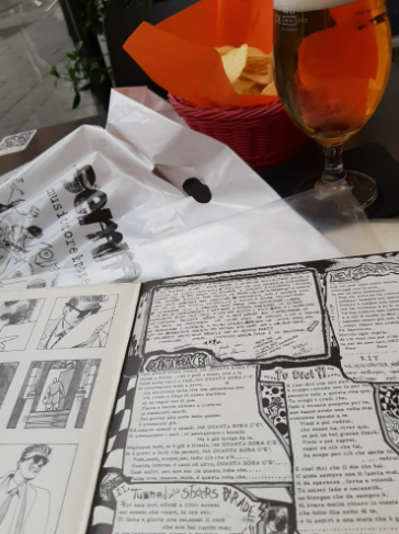foto dell'inserto del disco in primopiano con disegni e scritte in biancoe nerostilepunk, dietro c'è un bicchiere con spritz e si vede anche la busta del negozio semm